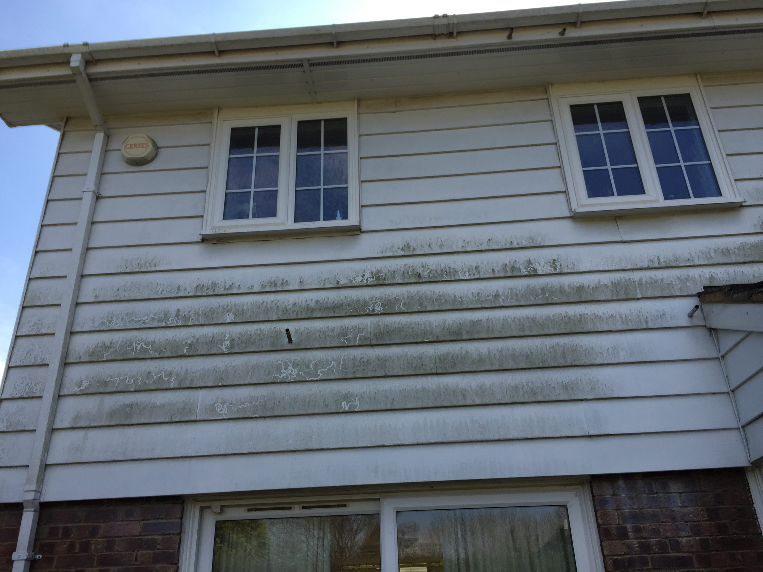 Dirty, algae-streaked UPVC cladding before cleaning